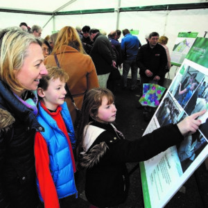 A woman and two children pointing at a display board with information about updates to the outline planning application for the northern part of Manydown.